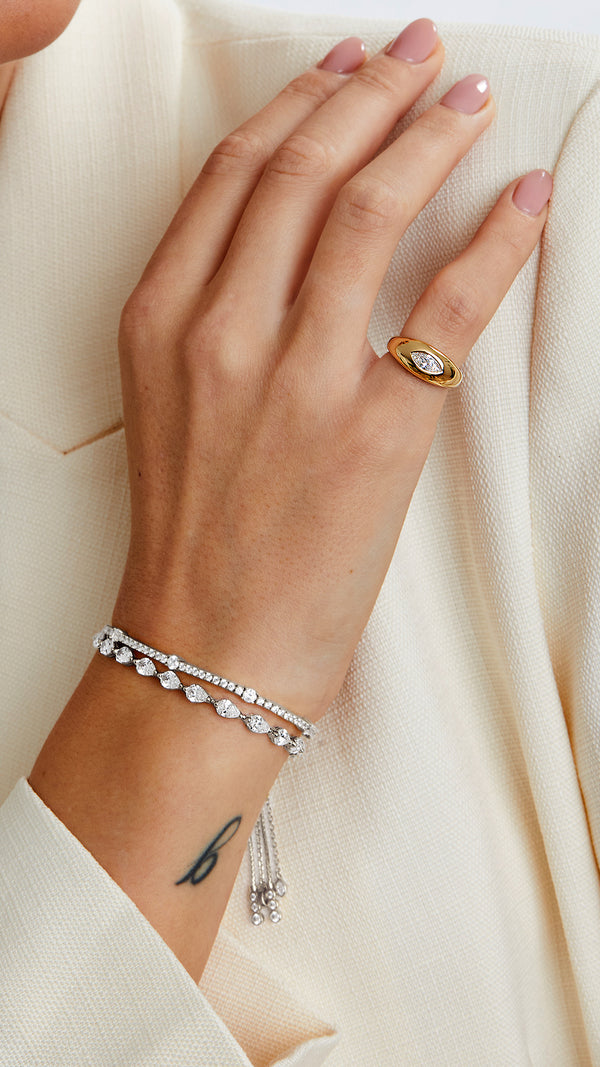 Sterling silver slider bracelets with pear-shaped stones paired with a gold signet ring.