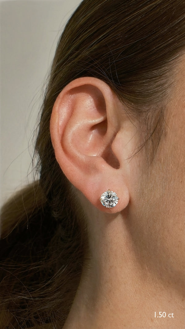 A model showcasing 1.50 carat round brilliant solitaire stud earrings set in 9K yellow gold, featuring a secure double notch post for a perfect fit.