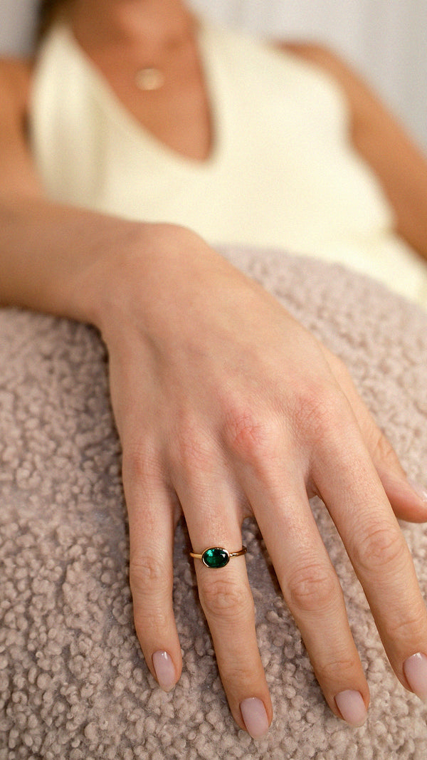 Gold baby cocktail ring with a smooth oval green stone.