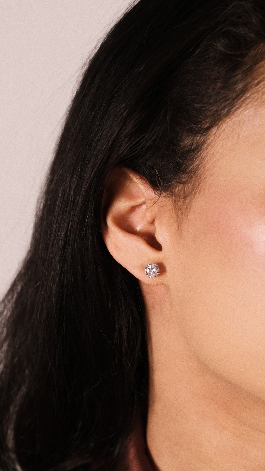 Close-up of an ear wearing a diamond style 1ct stud earring with a neutral background
