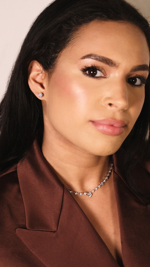 Woman wearing a brown satin jacket with a close-up of 1ct stud earrings.
