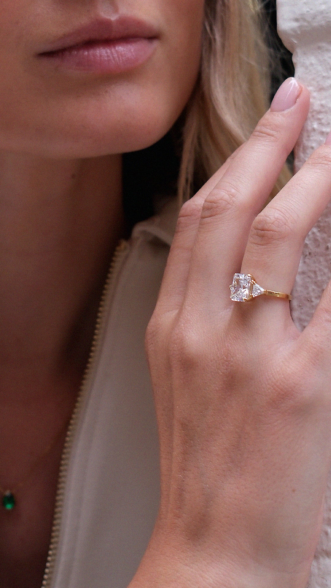Close-up of a hand wearing a diamond style trilogy ring with sparkling side stones.