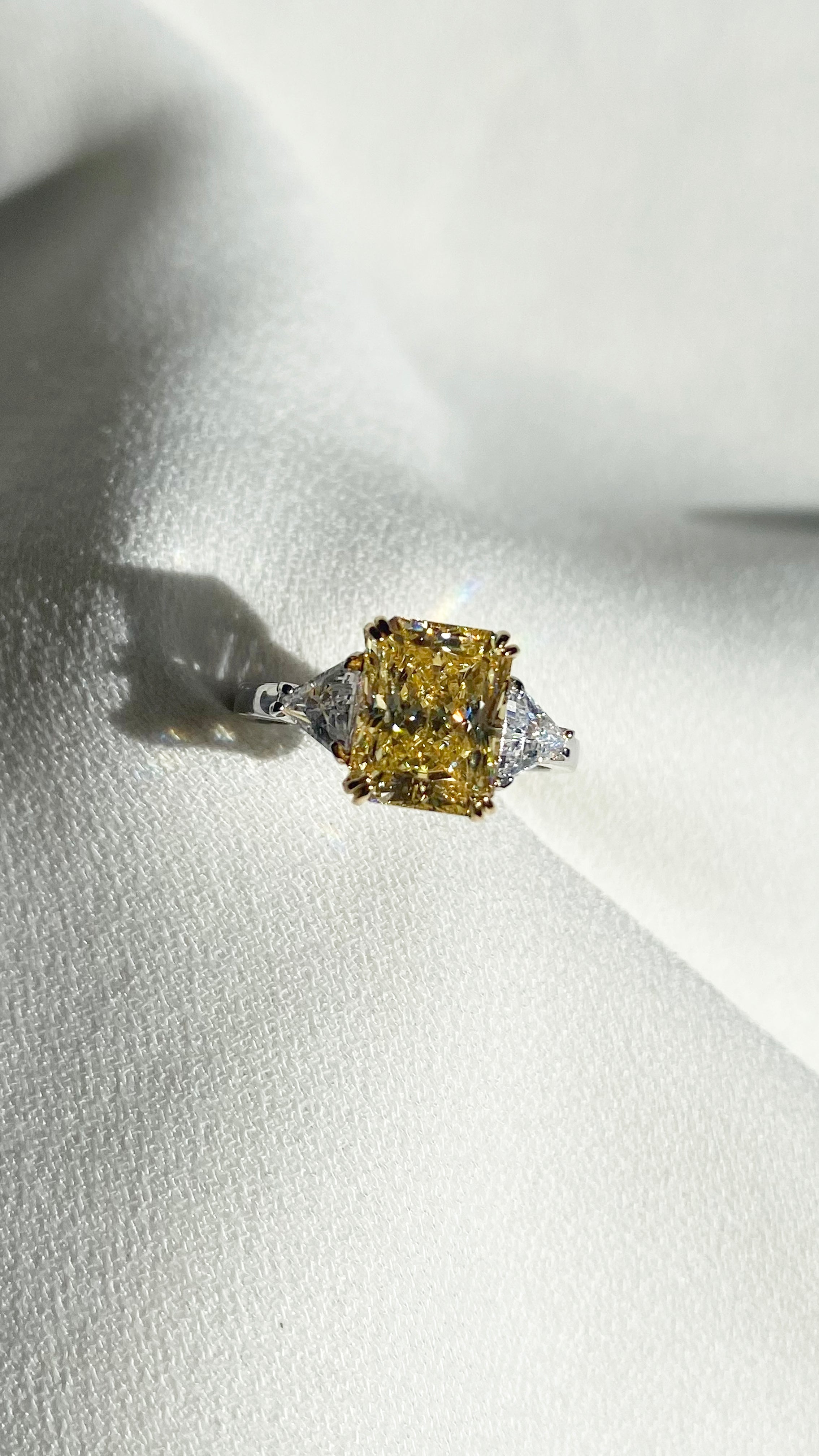 Diamond style light yellow radiant cut gemstone trilogy ring with sparkling side stones.