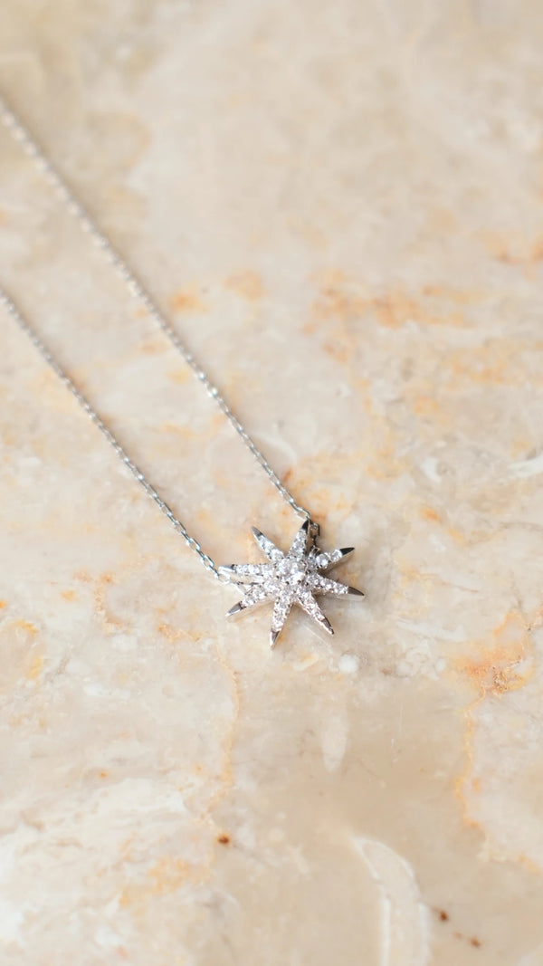 Sterling silver star pendant necklace with white gold plating and round brilliant stones.