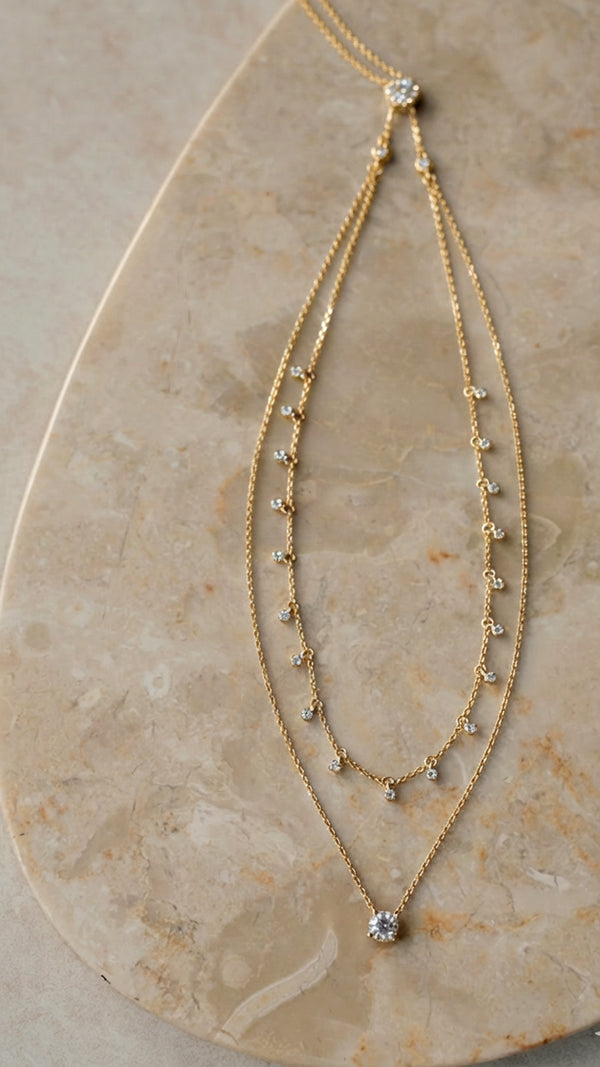 Pre-layered necklace with adjustable slider clasp, featuring bezel-set rounds and a solitaire drop in gold.