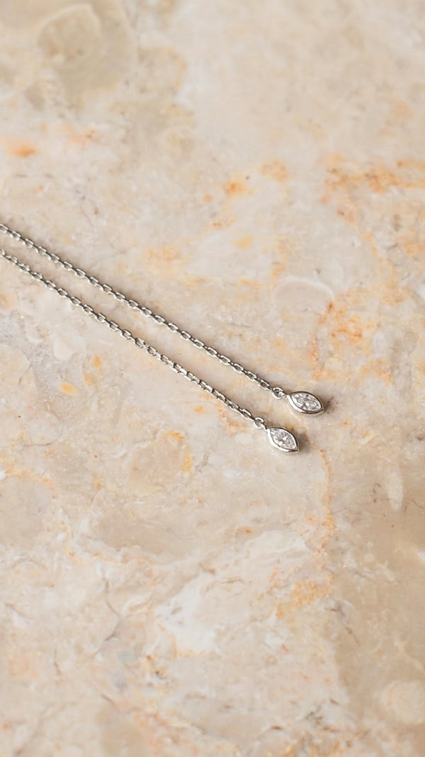 Silver necklace with small gemstones on the end of an adjustable slider. 