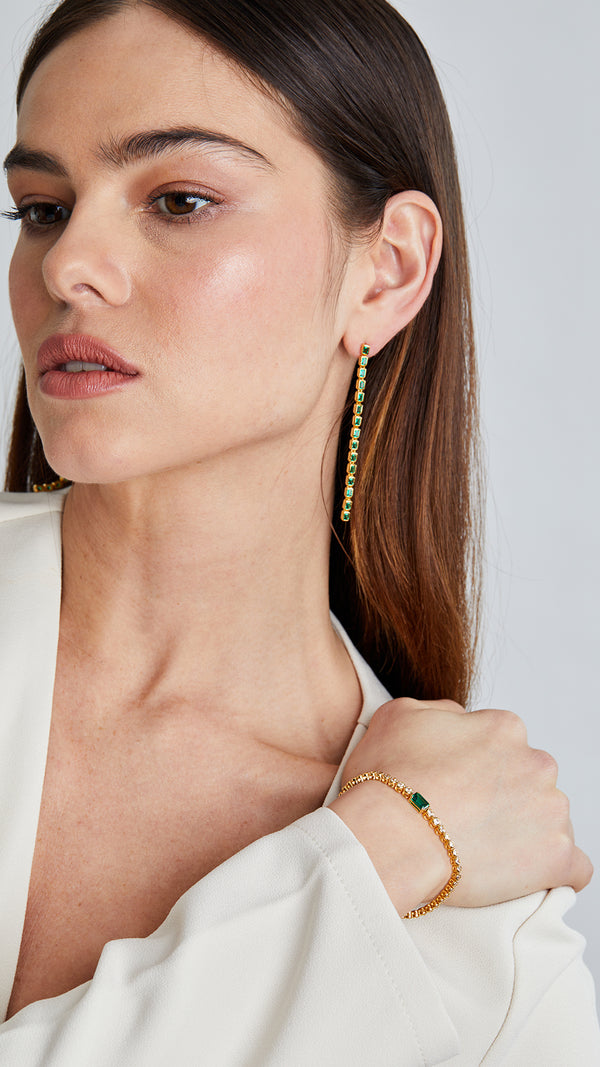 Gold slider bracelet with emerald center stone paired with Cassidy emerald drop earrings