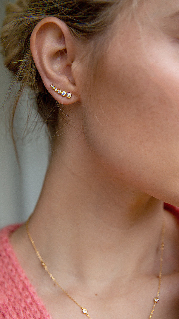 Close up of gold vermeil ear climbers featuring graduated round stones.