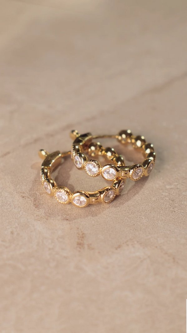 Close up of gold vermeil bezel set round gemstone hoops showing the secure locking clasp mechanism.