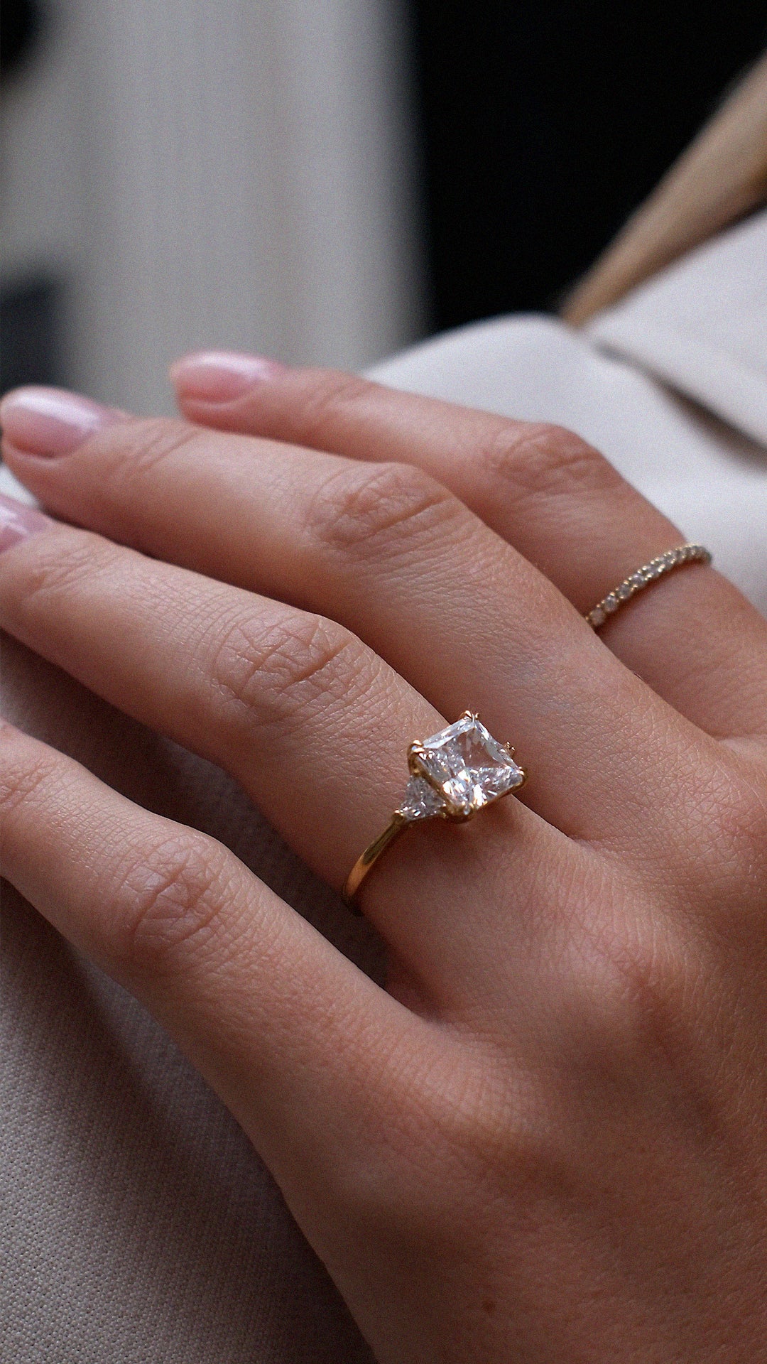 Close-up of a hand wearing a diamond style trilogy ring with triangle shoulder stones.