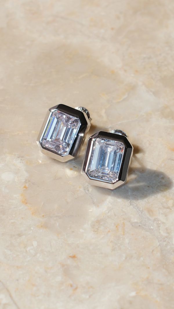 Sterling silver Lily earrings featuring a sparkling clear emerald-cut stone.