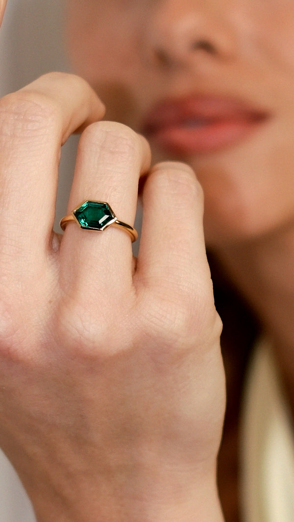 lose up of Demi gold ring featuring a hexagon-shaped emerald green stone.