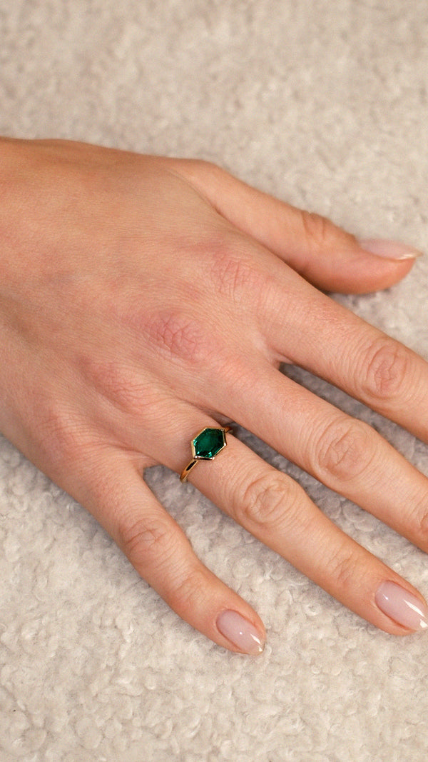 Top-down view of a bezel set hexagon ring with a green gemstone.