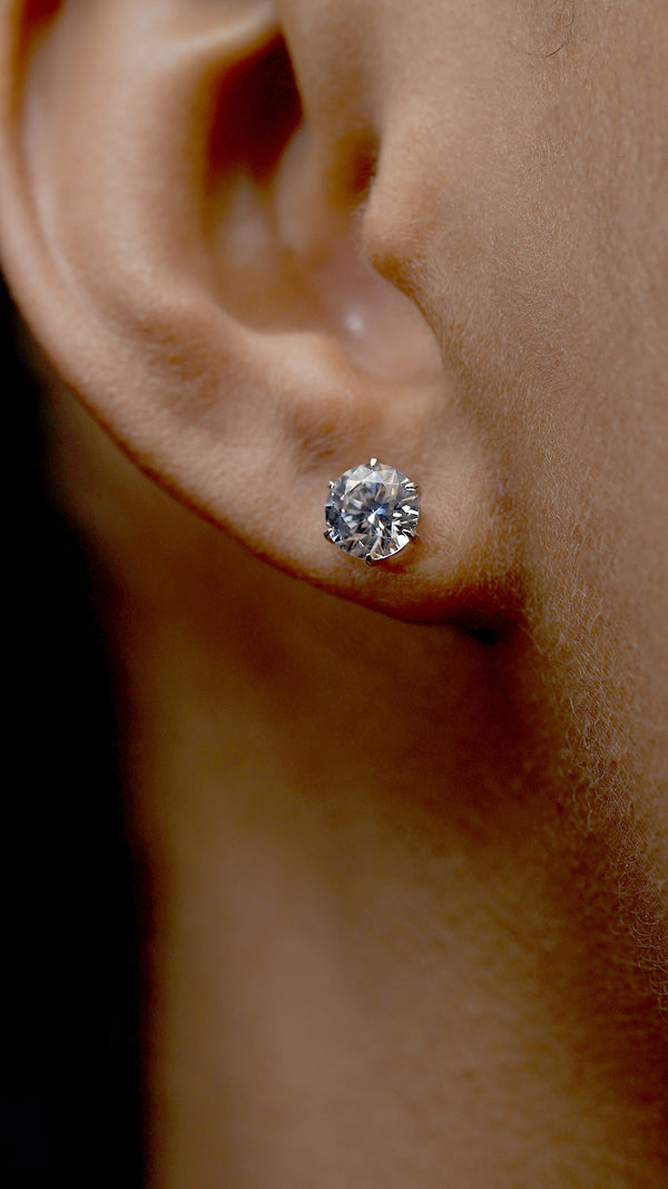 Close-up of a diamond earring on an ear with a blurred background