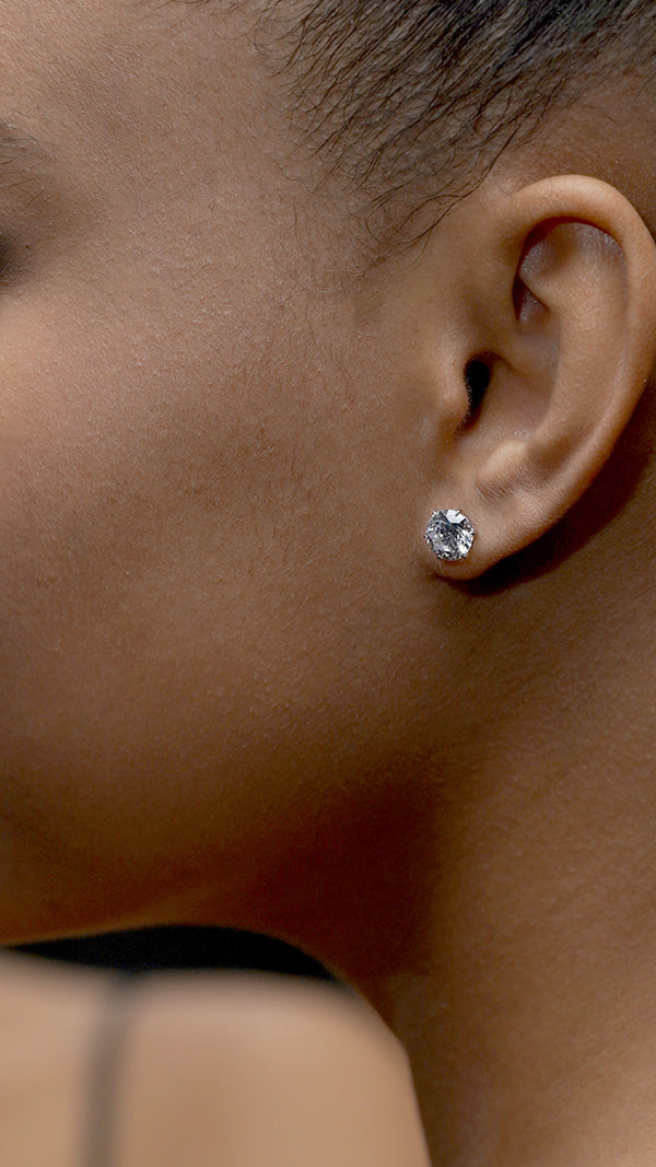 Close-up of an ear wearing a solid white gold diamond stud earring.