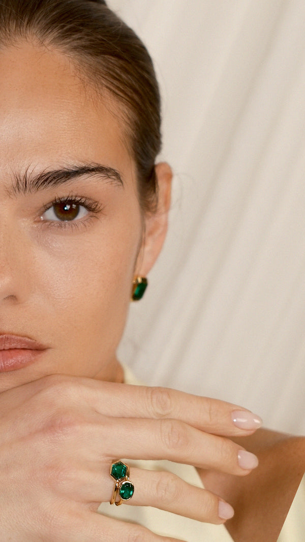 Two gold vermeil rings with green stones layered for a stacked look.