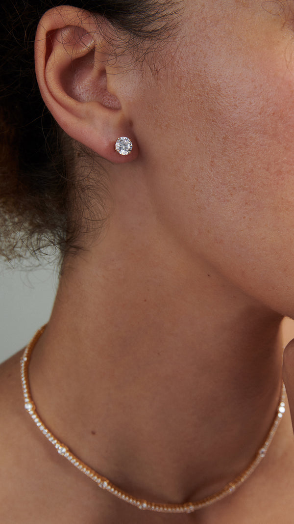 Close-up of a timeless yellow gold flush-fitting stud earring on the ear.