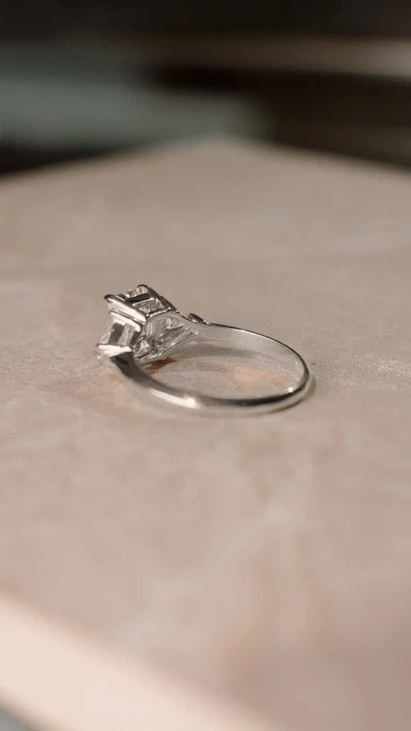 Sterling silver ring with a trilogy design and radiant cut gemstone with triangular side stones.