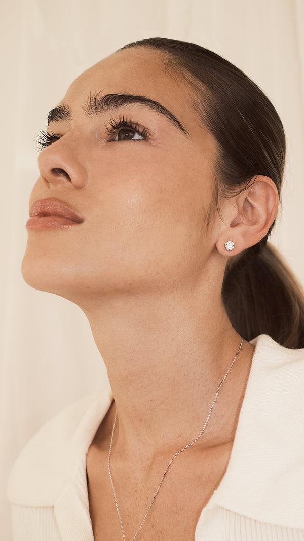Woman wearing diamond style 0.75ct stud earring and necklace against a neutral background