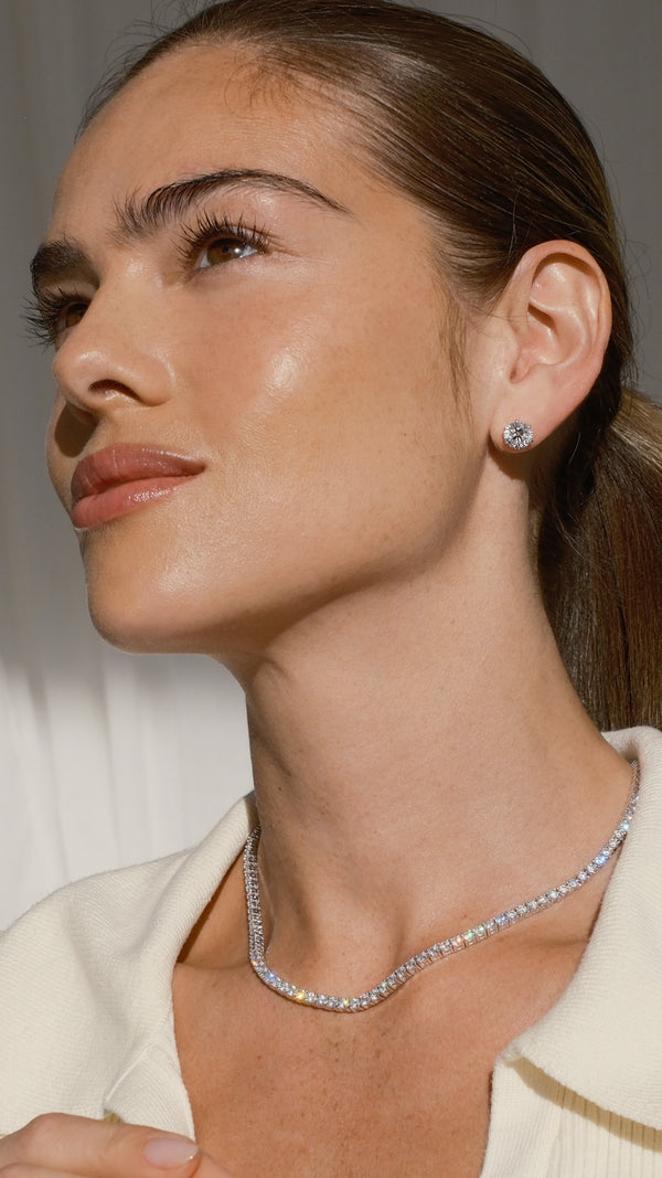 Close-up of an ear wearing a diamond style stud earring in 9k solid white gold paired with a classic tennis necklace. 