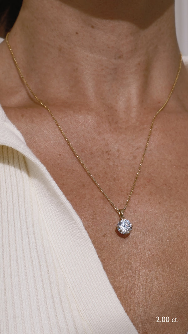 Solid gold necklace with a diamond style 2ct pendant on a person's neck