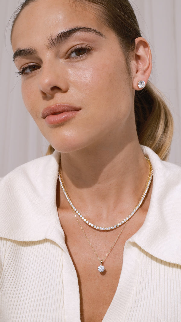 Model wearing a 9k solid yellow gold necklace with a 1ct pendant paired with a gold vermeil classic tennis necklace.