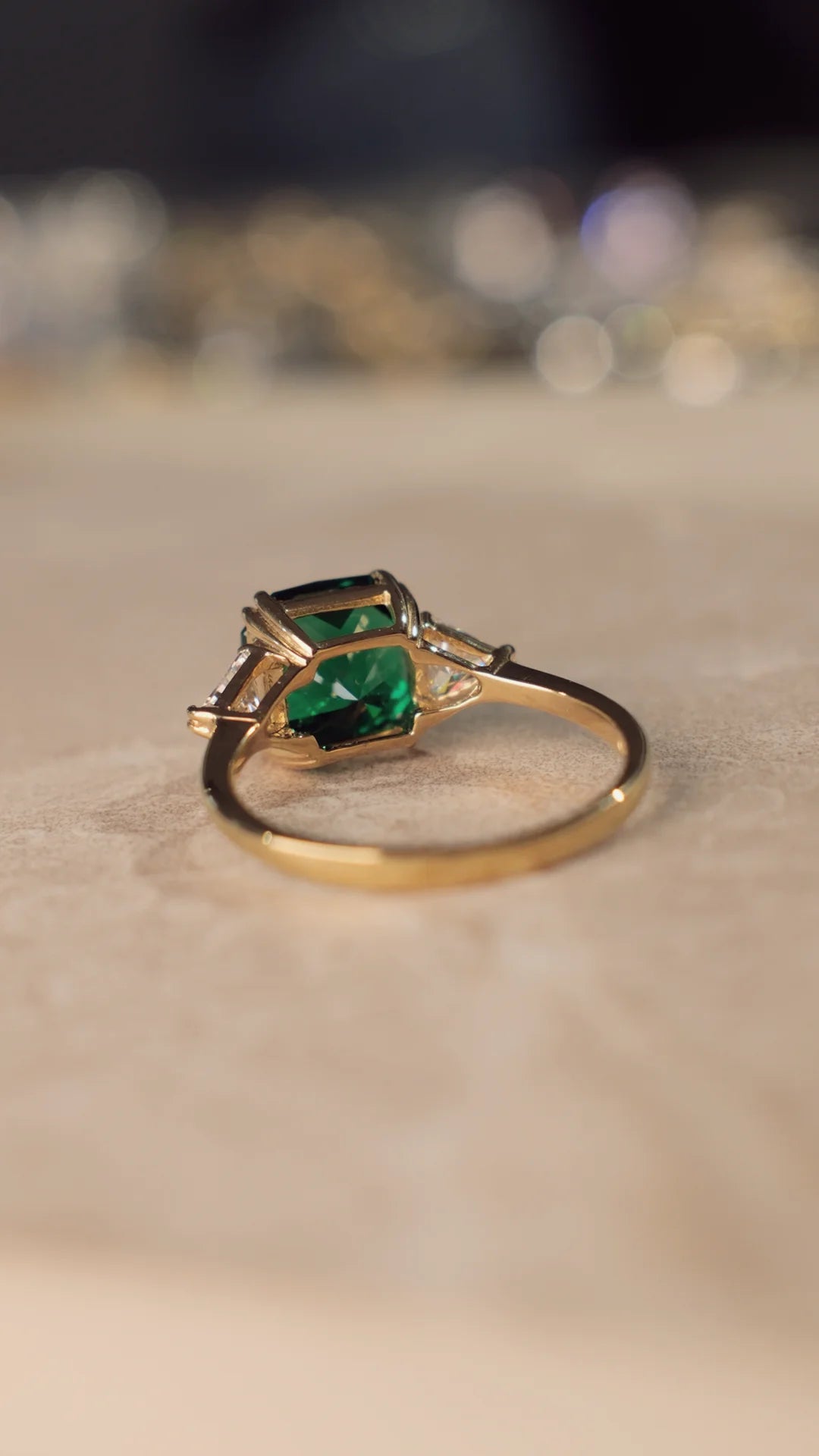 Gold ring with emerald green flanders cut gemstone on a textured surface