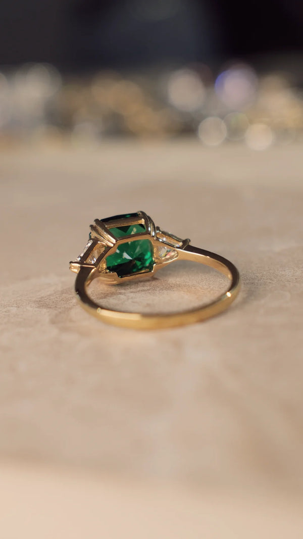 Gold ring with emerald green flanders cut gemstone on a textured surface