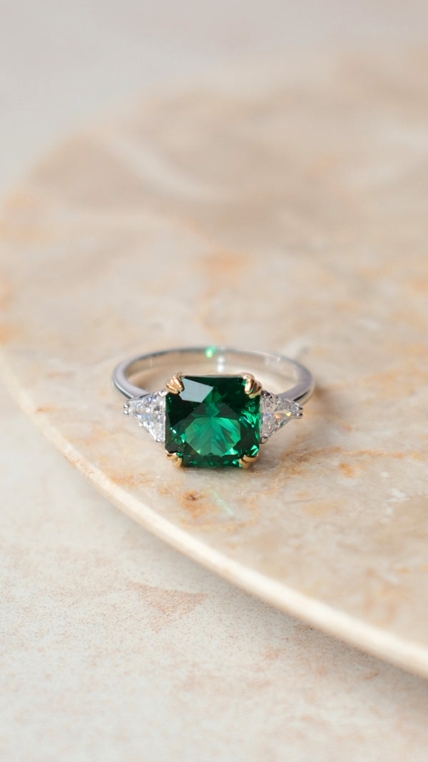Close-up of deep emerald green gemstone with 61 facets in a double prong setting