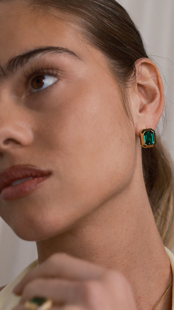 Close-up of the Lily emerald stud earrings in 18K gold vermeil, featuring a chunky bezel and deep green stone