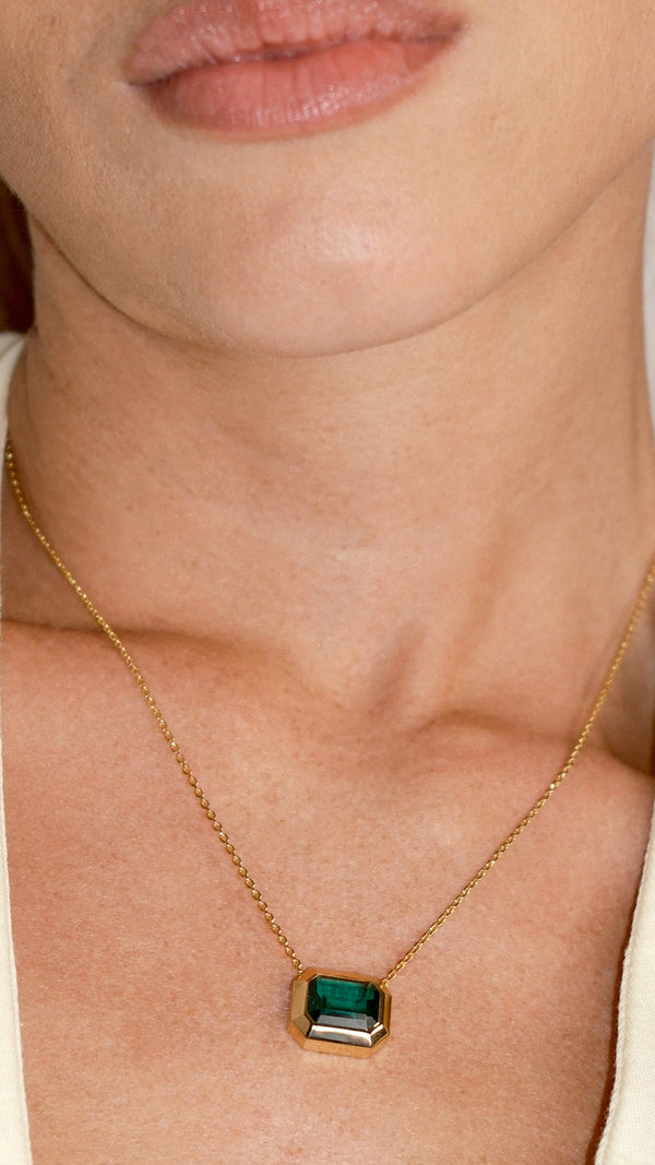 Close up of a bezel set emerald green slider necklace in gold vermeil.