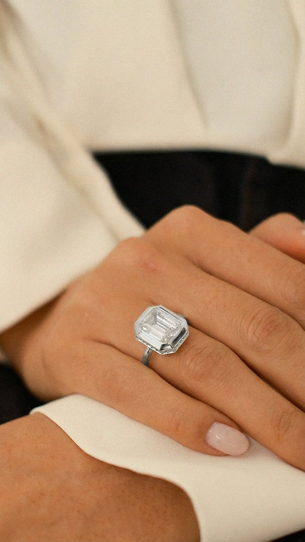 A model wearing the sterling silver Lily emerald-cut ring on her ring finger, styled with a white shirt and dark denim. 