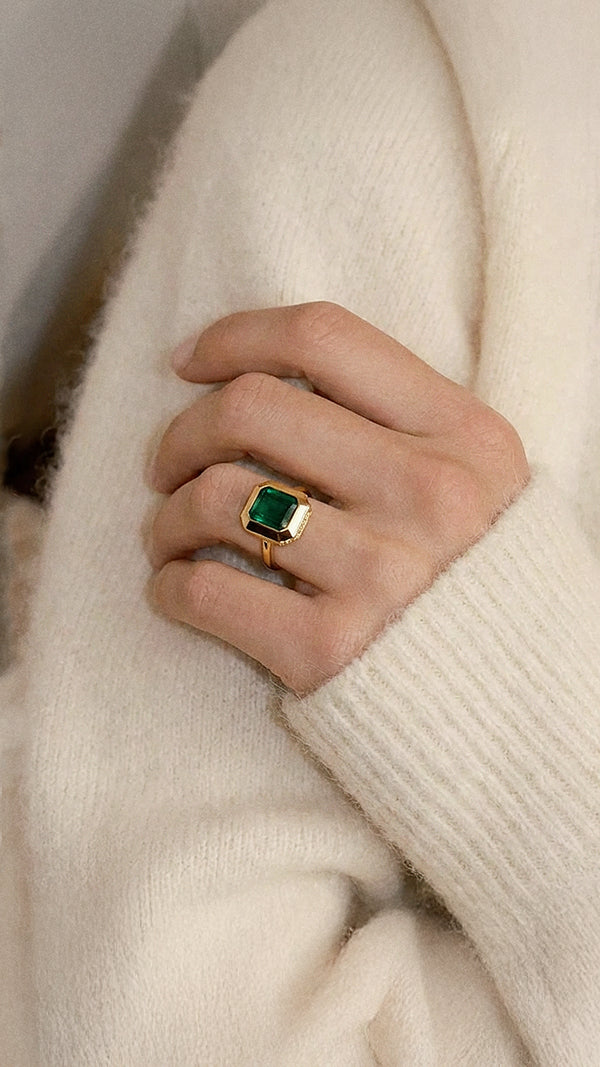 An emerald and gold bezel set ring styled with a cashmere jumper