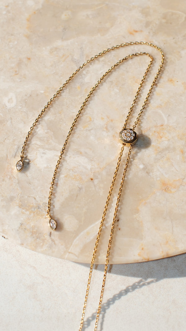 Slider detail of an adjustable gold vermeil chain necklace with gemstone detailing on the ends. 