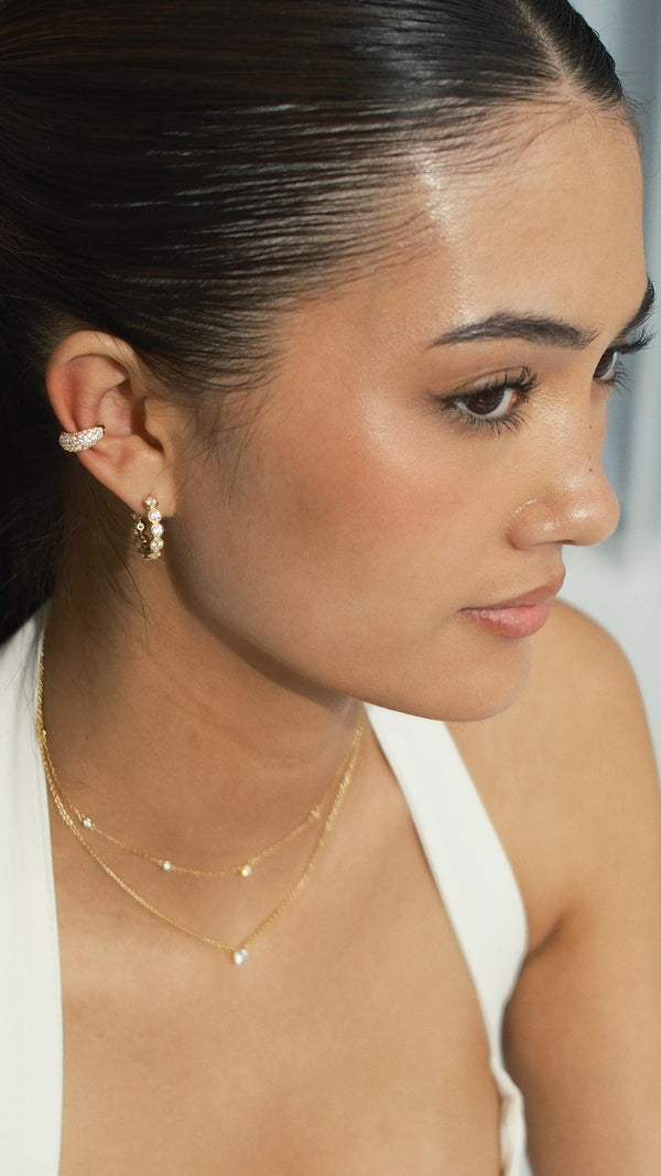 Gold round gemstones hoop earrings paired with a pave setting ear cuff earring in gold paired with a pre-layered gold necklace. 