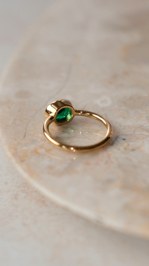 yellow gold vermeil solitaire ring featuring a horizontally set oval emerald in a bezel mount