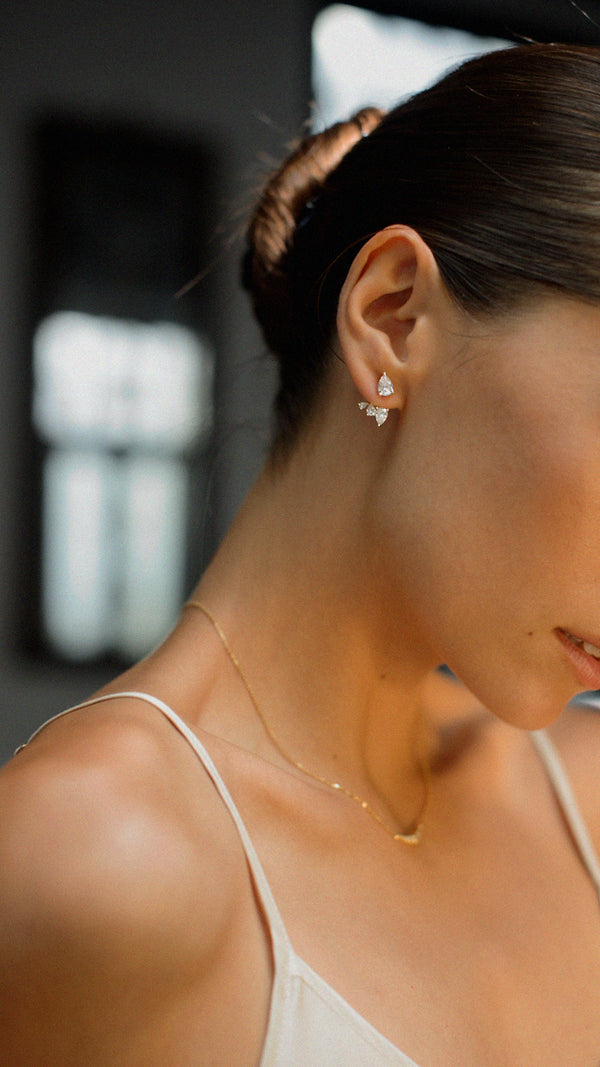 Close-up of gold vermeil earrings with cascading pear-shaped white stones