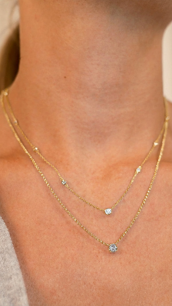 Close-up of a model wearing a double-layered gold necklace.