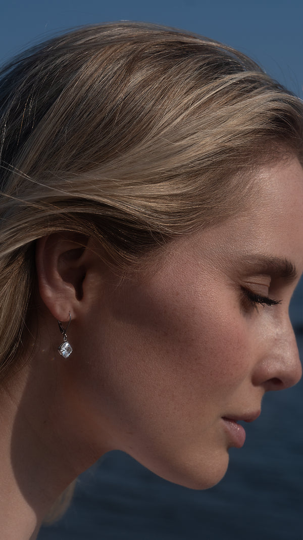 Elegant 9k solid white gold earrings with a suspended princess-cut gemstone.