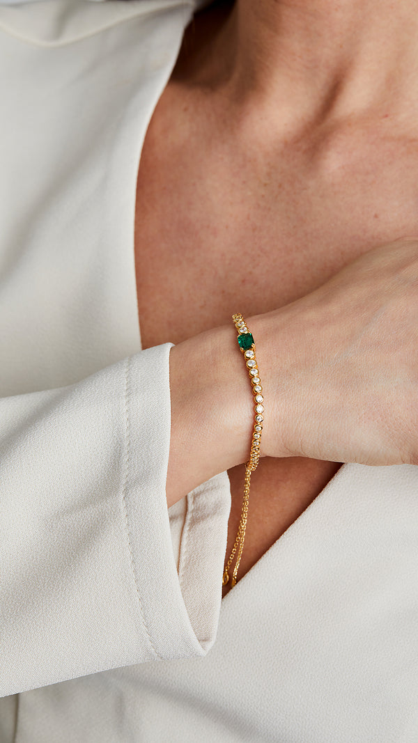 Bezel-set stone bracelet with adjustable slider. Gold with round and emerald-green gemstones.
