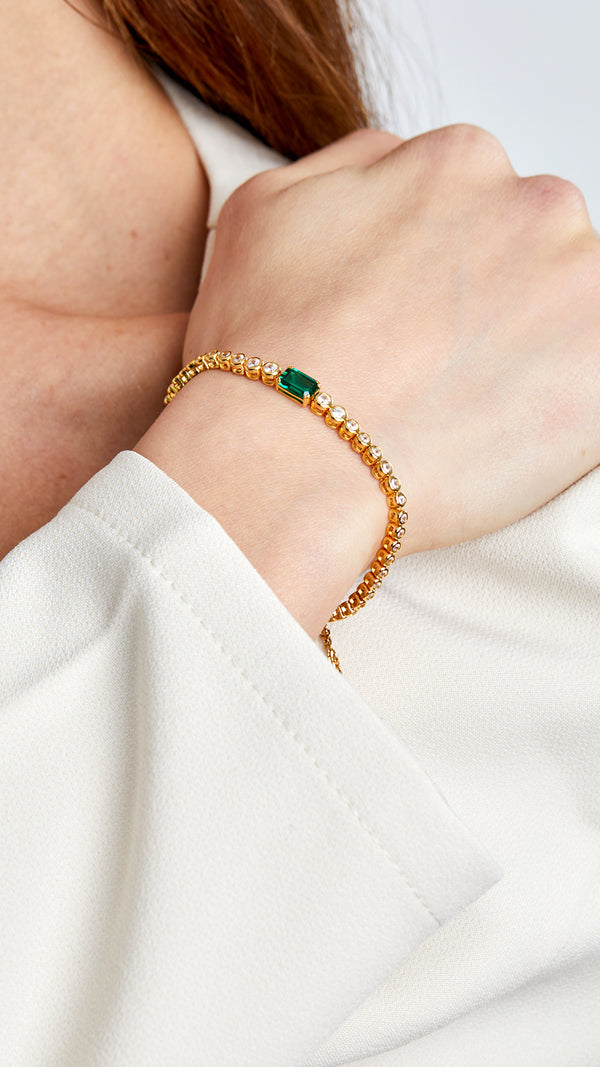 Brilliant-cut stone adjustable gold bracelet with emerald accent. 

