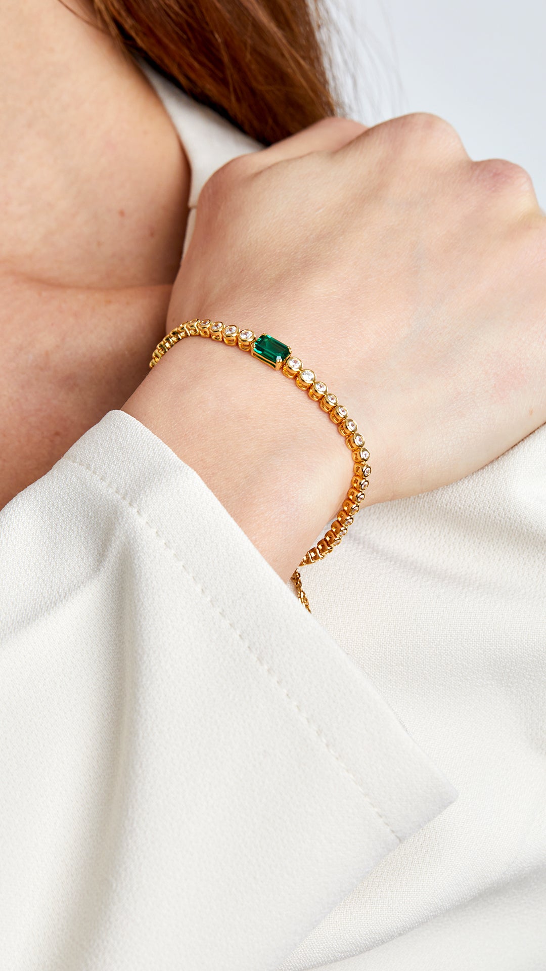 Brilliant-cut stone adjustable gold bracelet with emerald accent. 

