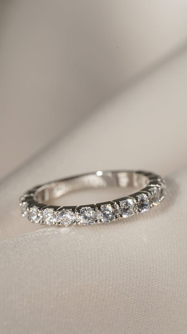 Close up of a sparkling solid white gold eternity band with a row of diamond like gemstones