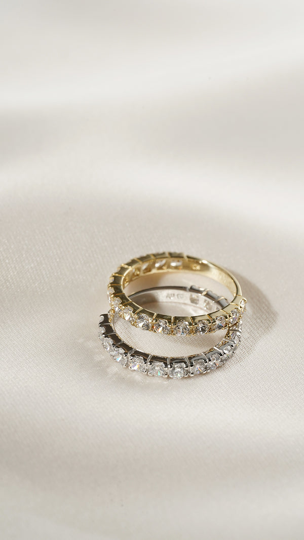 Solid white gold and solid yellow gold eternity rings stacked on top of each other. 