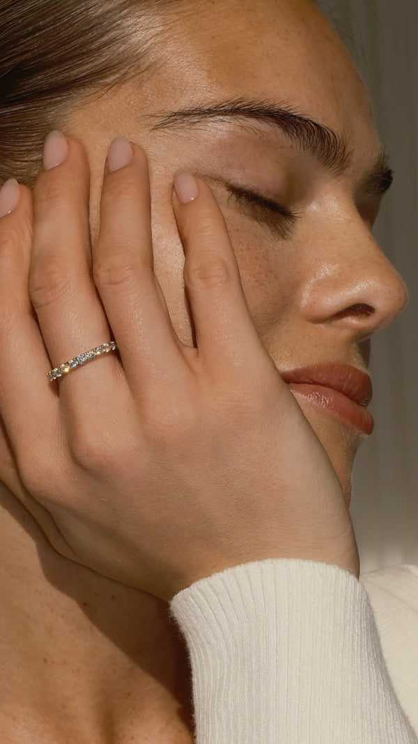 A womans hand wearing a solid 9k gold eternity ring on her finger