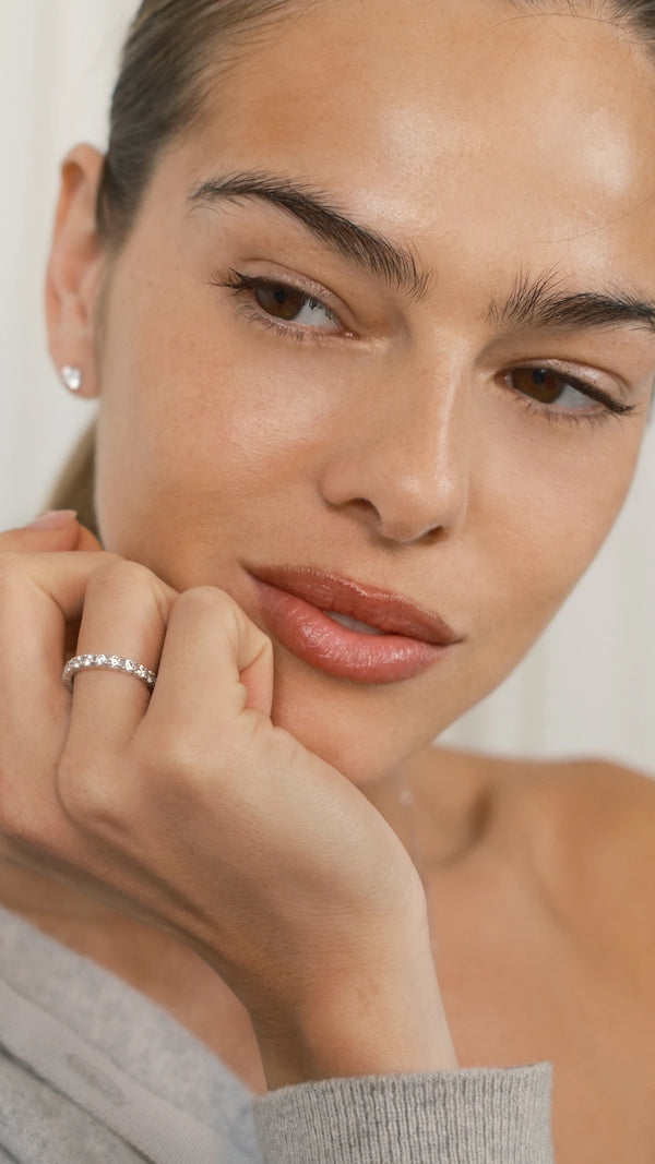 Close-up of a woman with a neutral expression, wearing a 9k white gold ring on her finger.