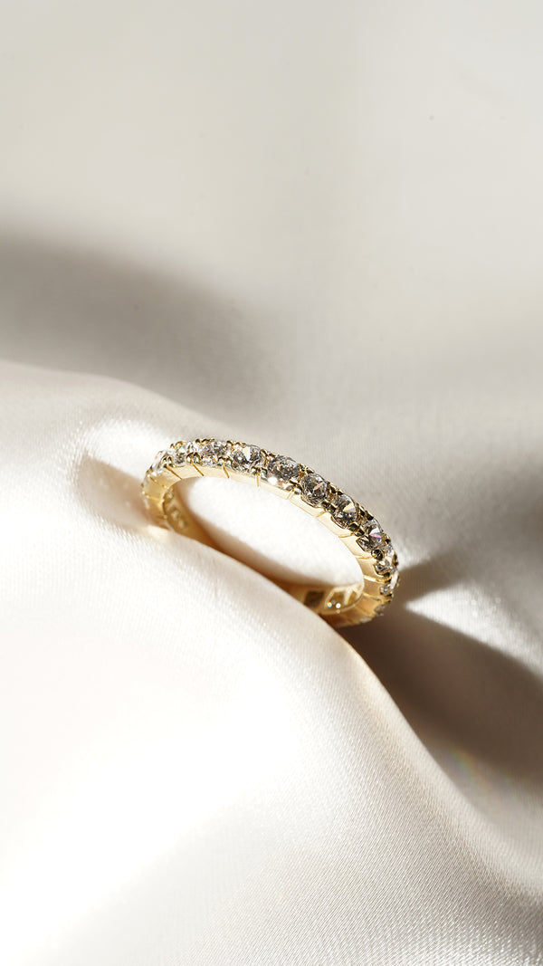 Top down view of the Raina solid gold eternity ring under direct light