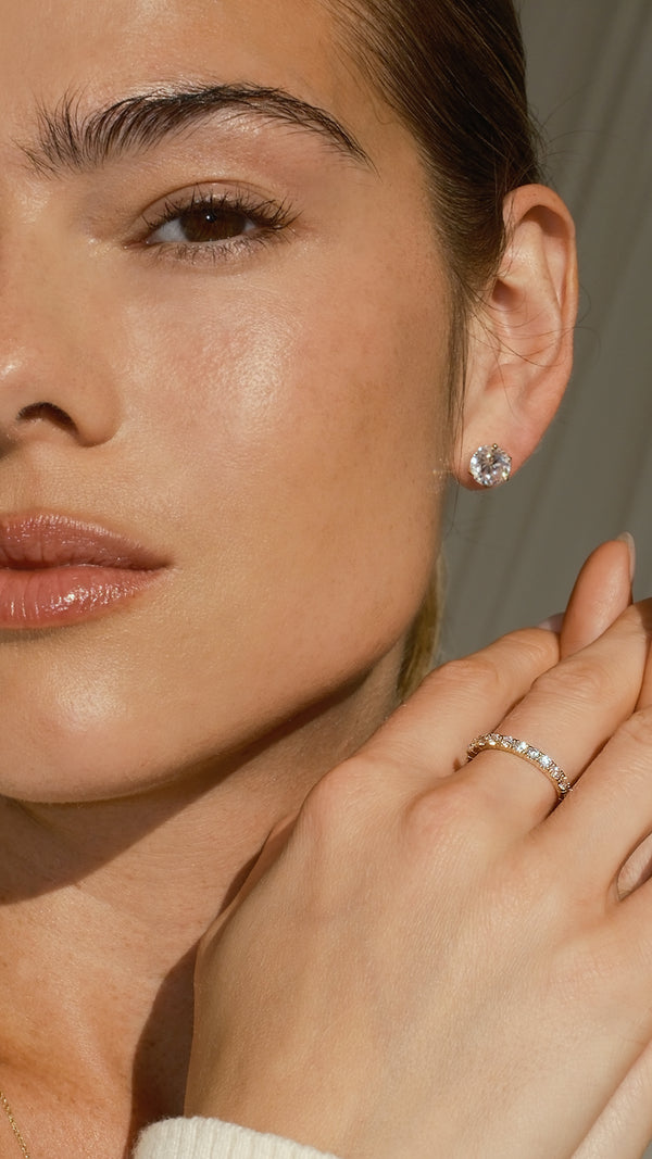 A woman wearing a lab-grown diamond stud earring with a diamond style solid gold eternity ring.