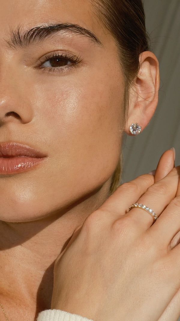A woman wearing a lab-grown diamond stud earring with a diamond style solid gold eternity ring.