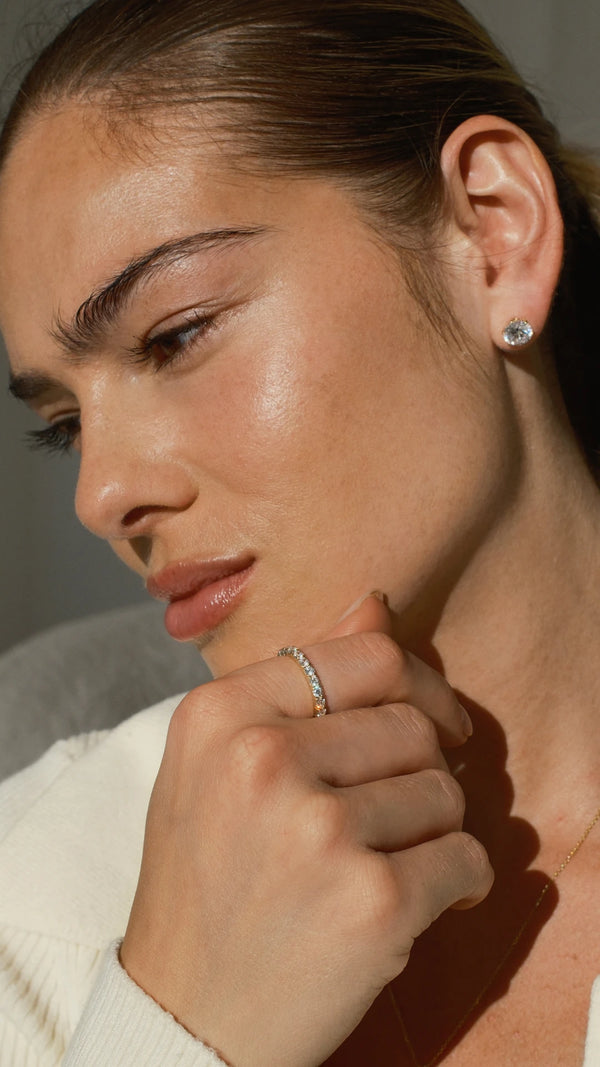 Close-up of a woman wearing lab grown diamond earrings and a solid gold eternity ring